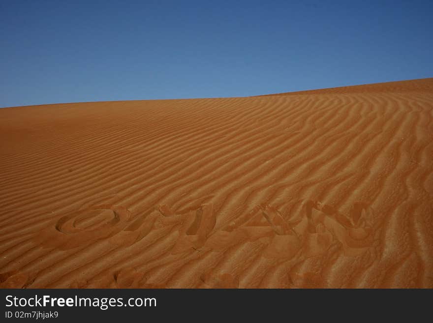 The word OMAN written in the desert sand