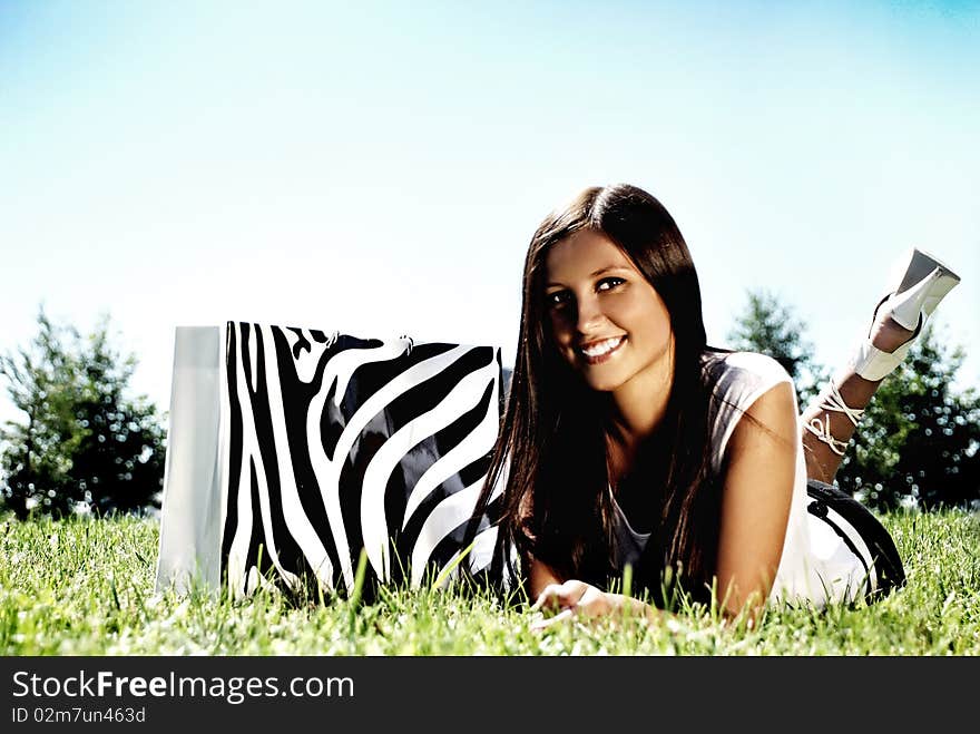 Fashion model with bag on a grass.