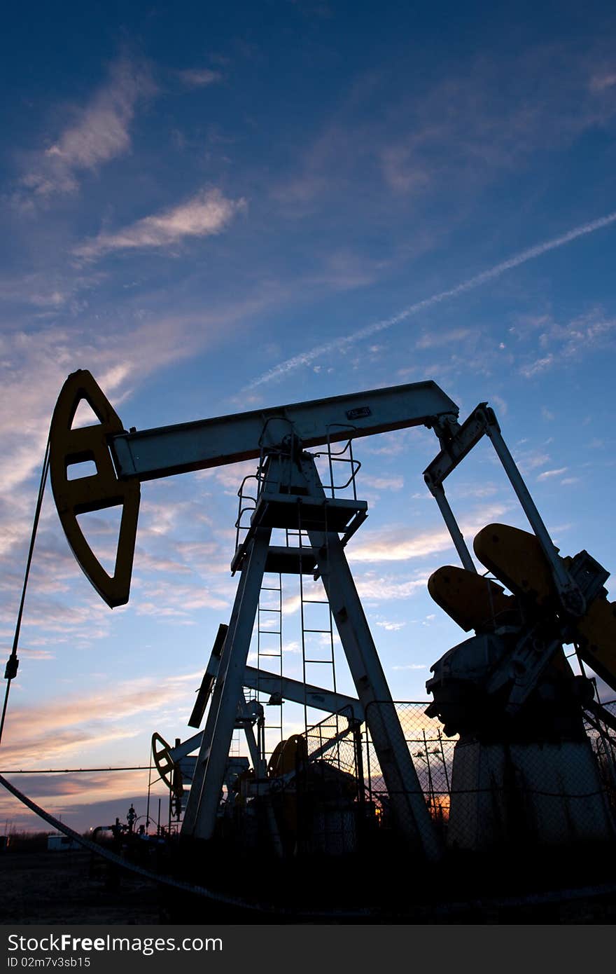 Oil pumps at sunset sky  background. Oil pumps at sunset sky  background