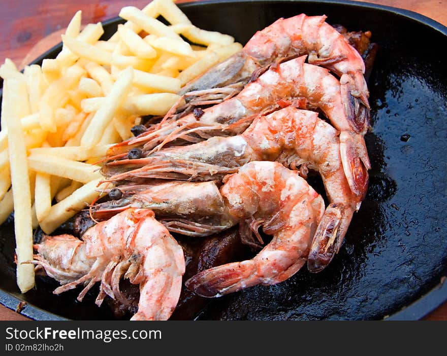 Prepared fried prawns and french fries on cast iron plate. Prepared fried prawns and french fries on cast iron plate