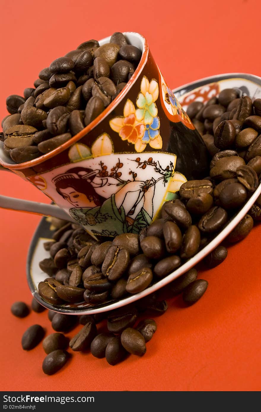 Coffee beans and cup on red background