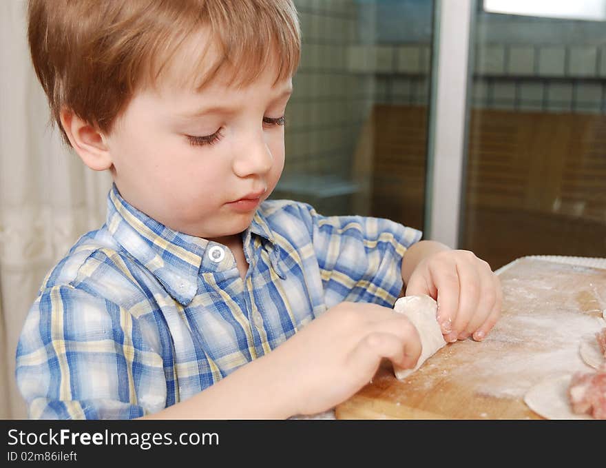 Little boy preparing russian meat dumplings