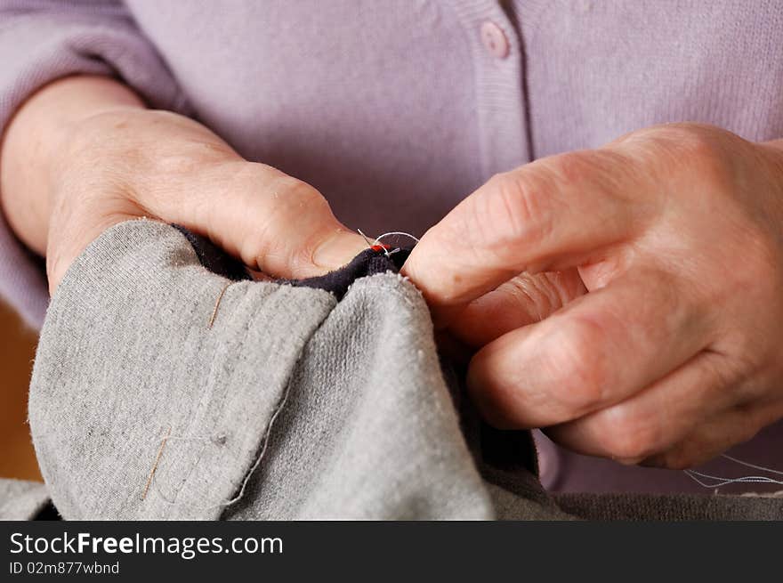 Hands of elderly woman repairing the clothes. Hands of elderly woman repairing the clothes