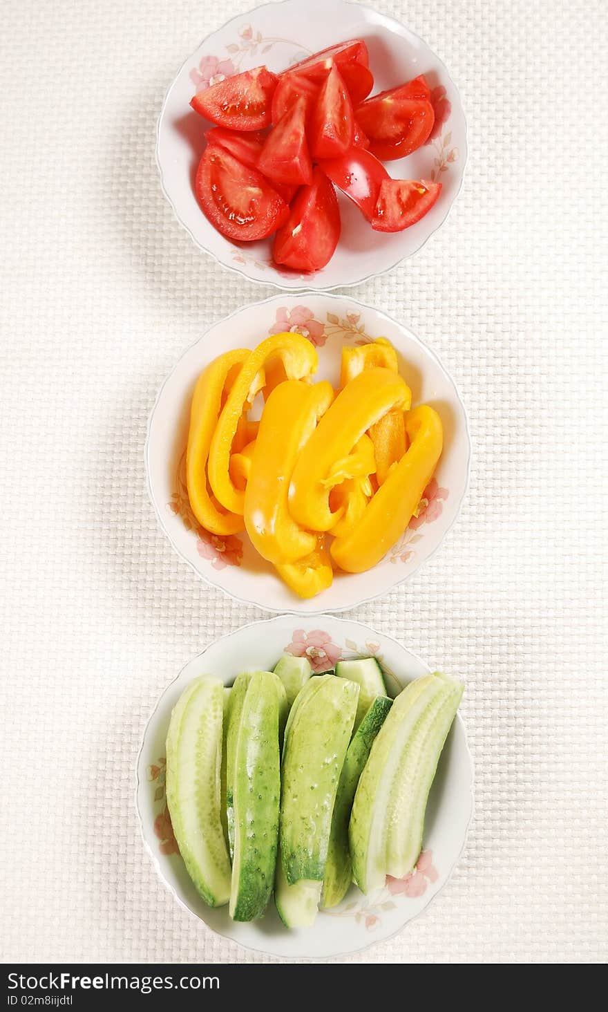 Sliced tomato, cucumber and bell pepper on the plates. Sliced tomato, cucumber and bell pepper on the plates