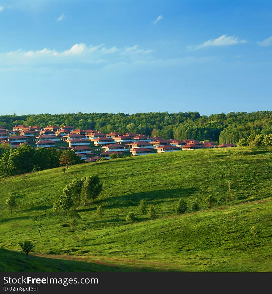 Green meadow against blue sky and small town