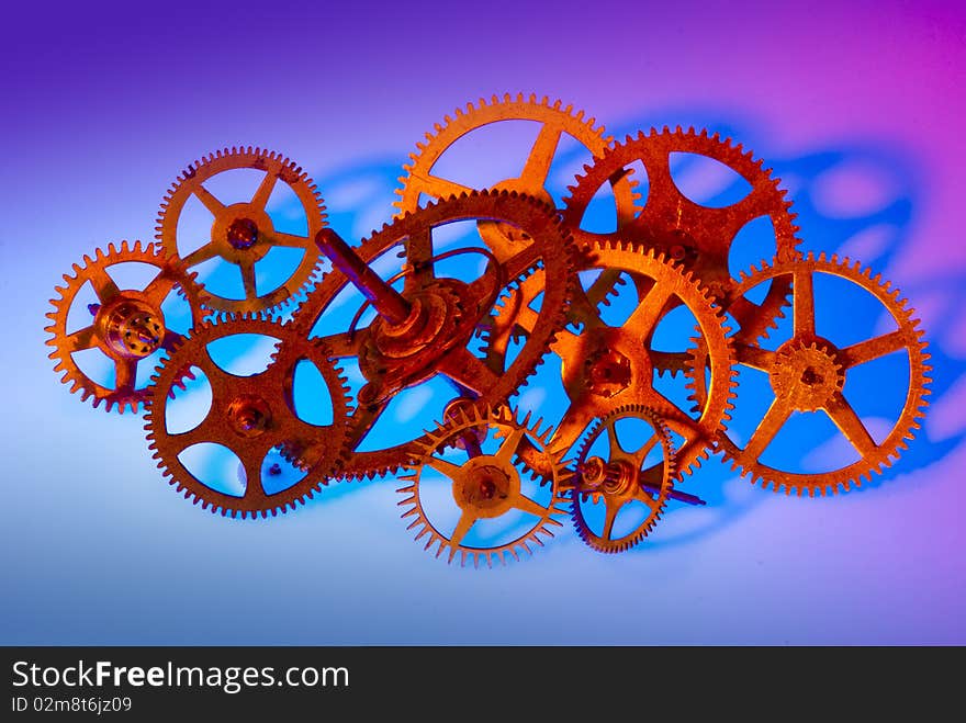 Various sized clock gears bunched together and lit with colored spot lights. Various sized clock gears bunched together and lit with colored spot lights