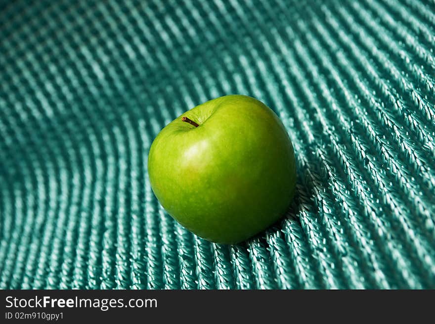 A green apple on blue background