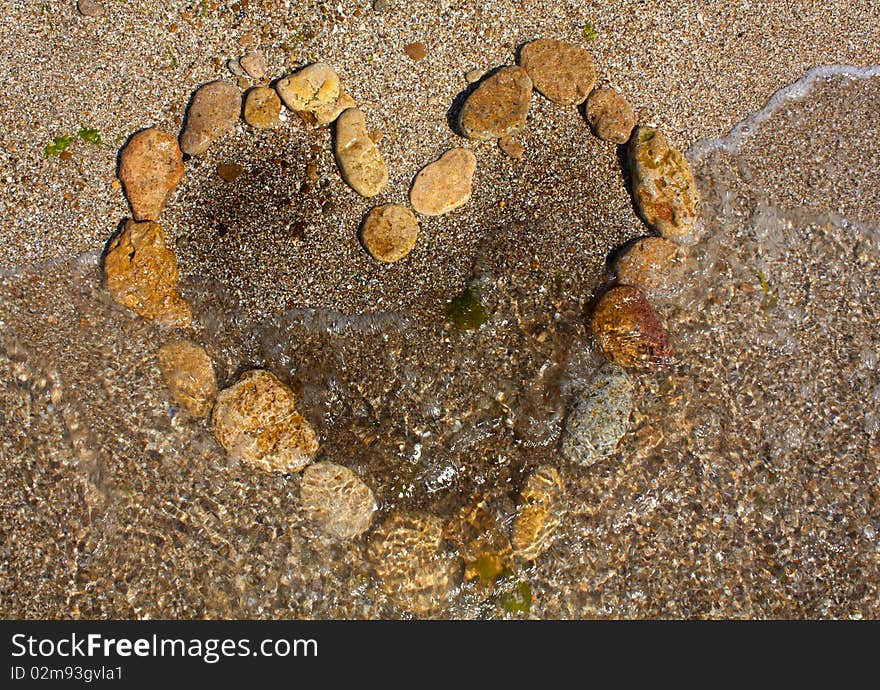 Heart from stones on sand seacoast