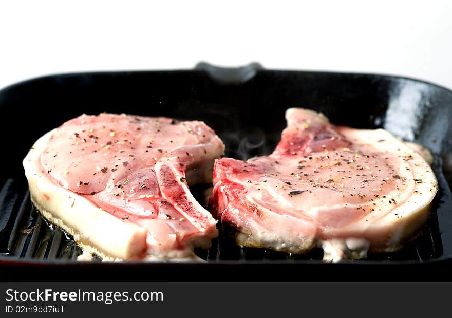 Close up of a pork chop cooking on a griddle pan. Close up of a pork chop cooking on a griddle pan