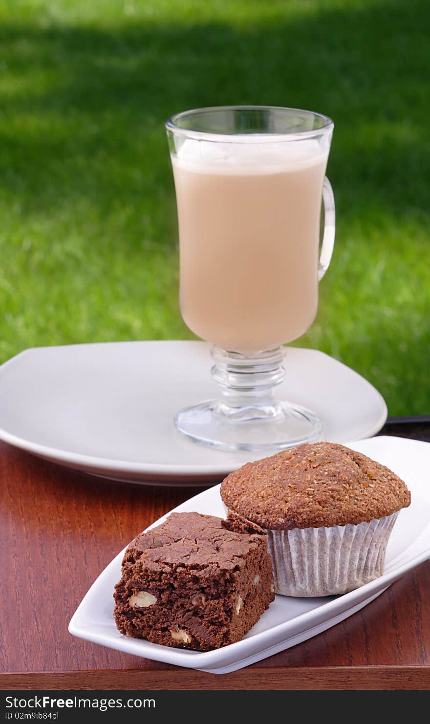 Chocolate brownie, bran muffin and iced cafe au lait on backyard tabletop. Chocolate brownie, bran muffin and iced cafe au lait on backyard tabletop