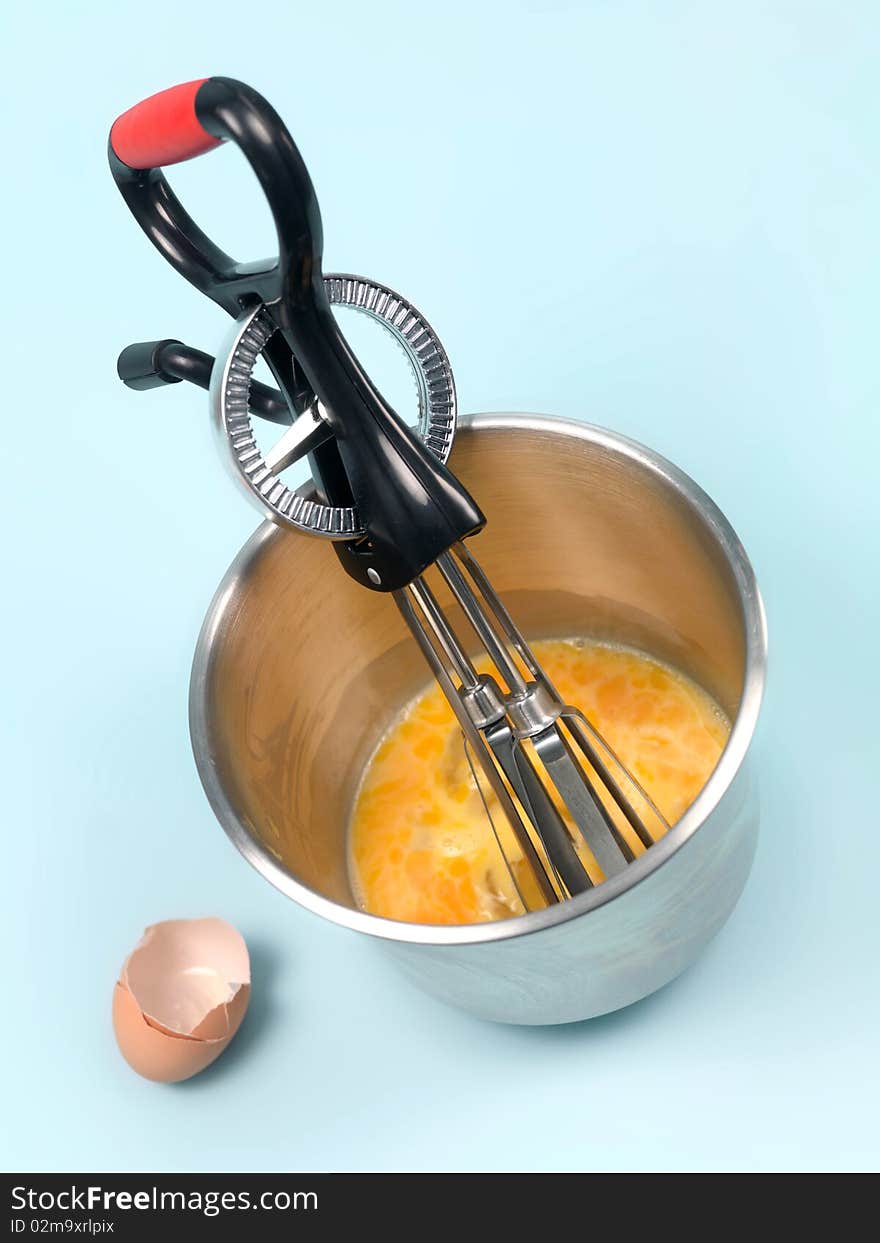 An egg beater eggs and a mixing bowl on a kitchen bench