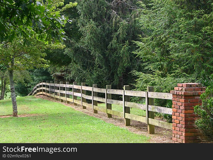 Rail fence and brick pillar, with trees in the background