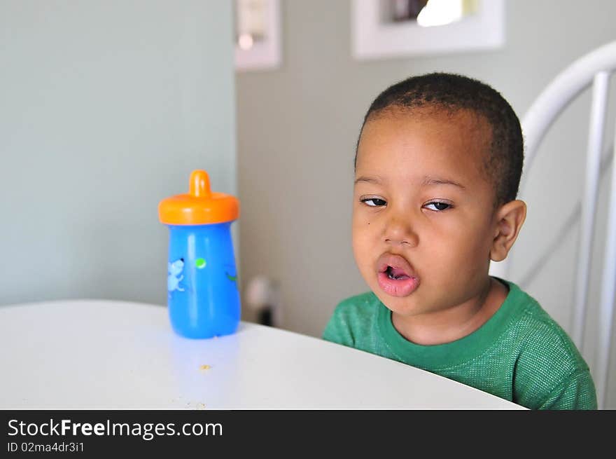 Boy at table enjoying drink with comical face to show he enjoy it. Boy at table enjoying drink with comical face to show he enjoy it