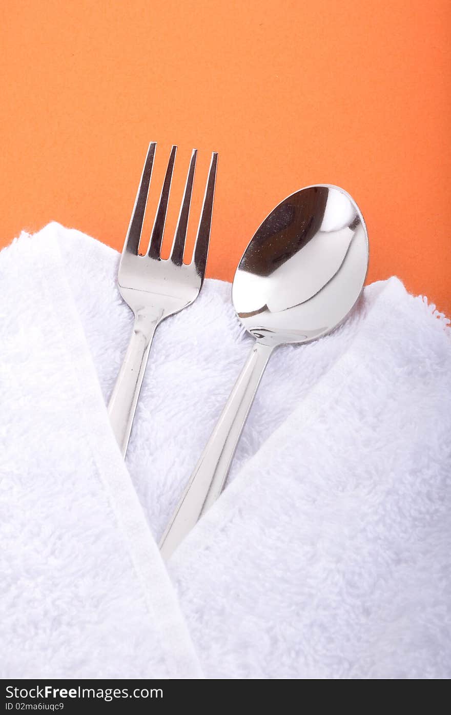 Place setting fork and spoon on orange background