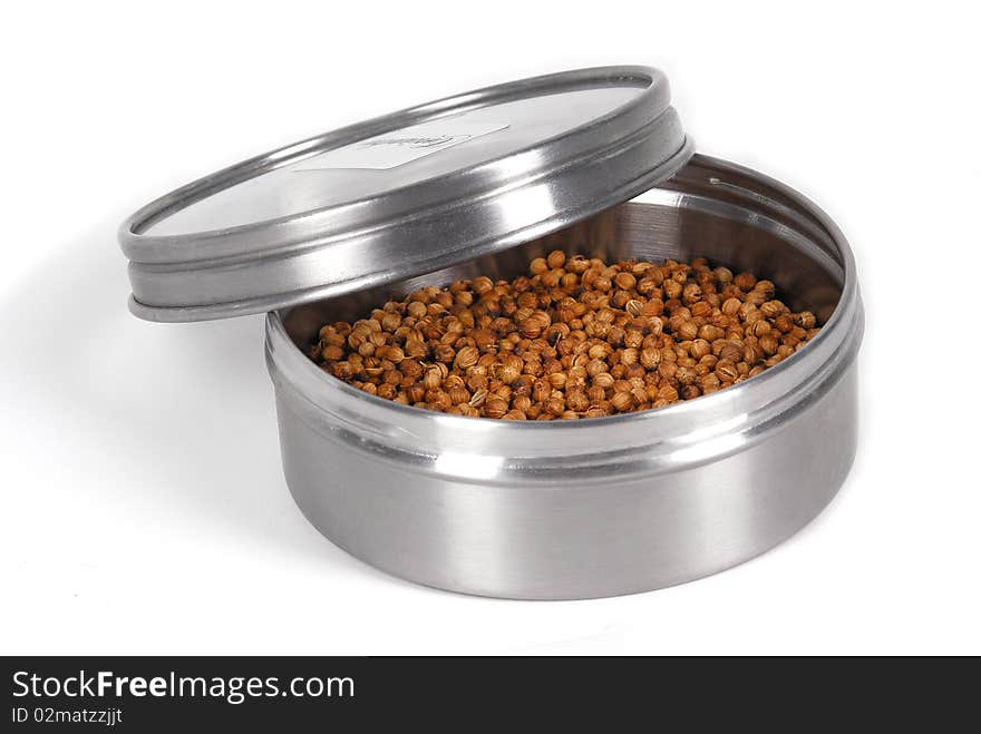 Coriander seeds in metal box on white background