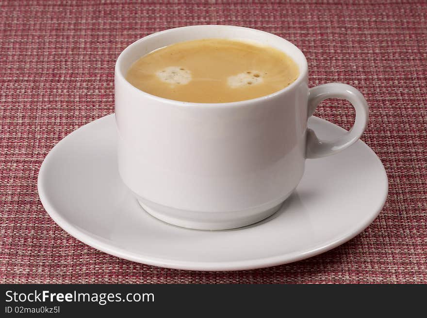 Little white espresso coffee cup on a white saucer over checked table-cloth background