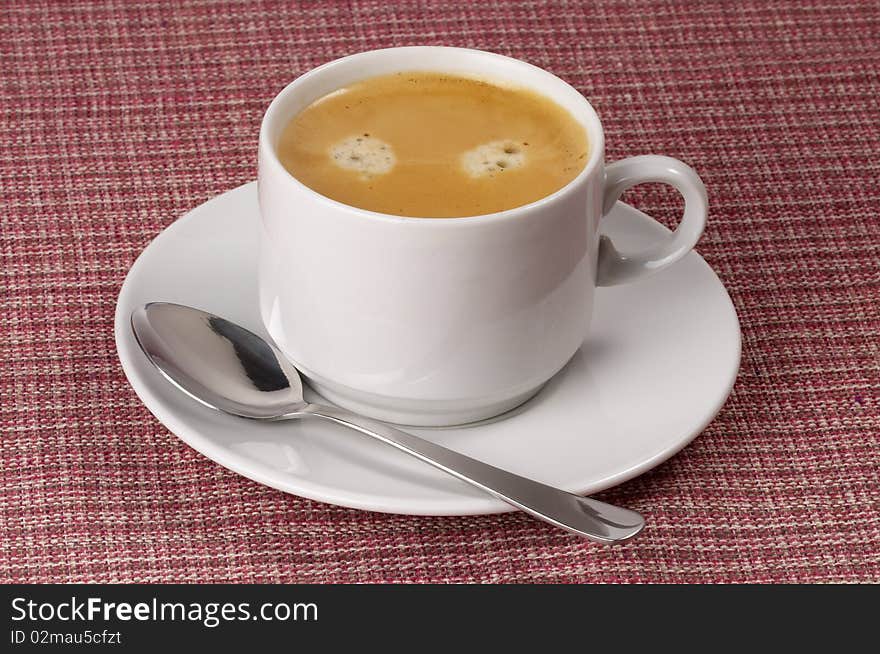 Little white espresso coffee cup on a white saucer over checked table-cloth background