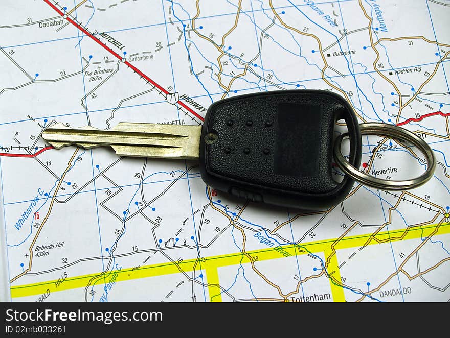 A single car key sitting on a road map background. A single car key sitting on a road map background