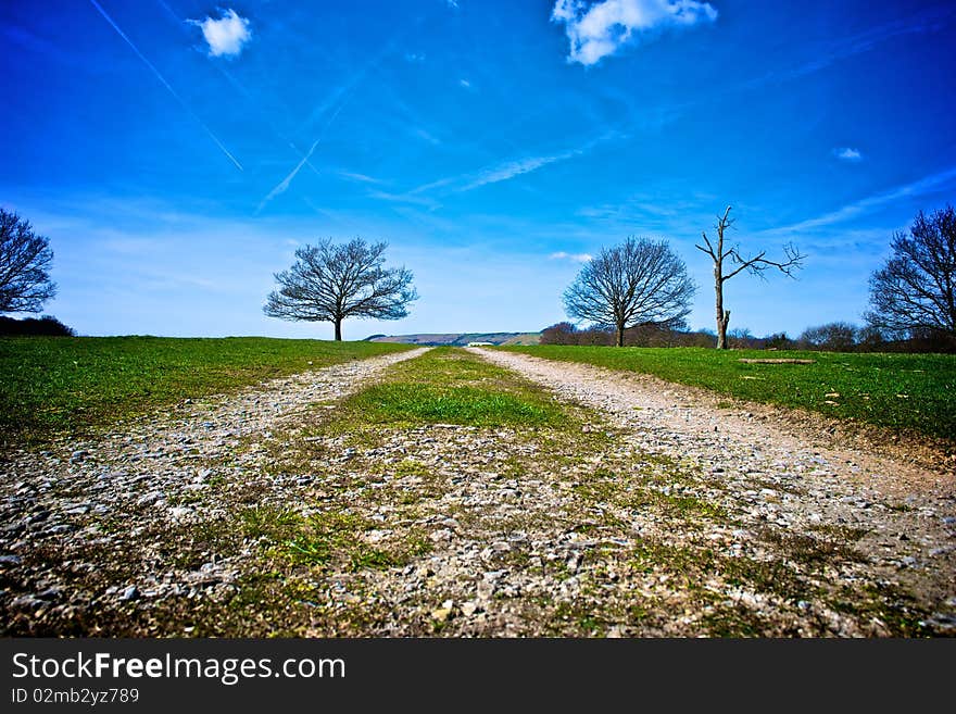 Track receding through countryside with blue sky and cloudscape background. Track receding through countryside with blue sky and cloudscape background.