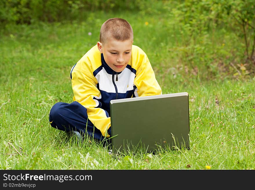 The boy with the computer on a grass