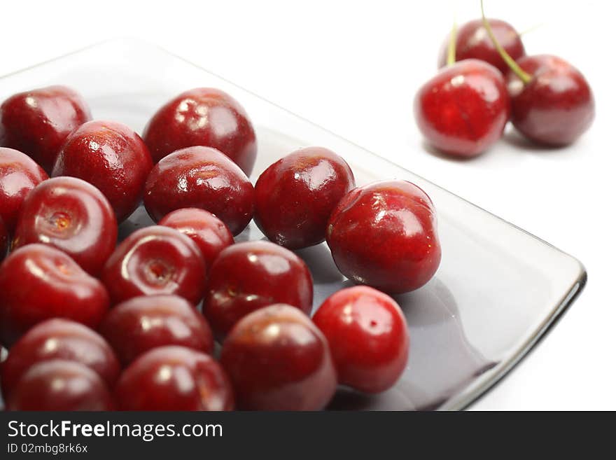 Heap of sweet cherries in a glass plate isolated on white