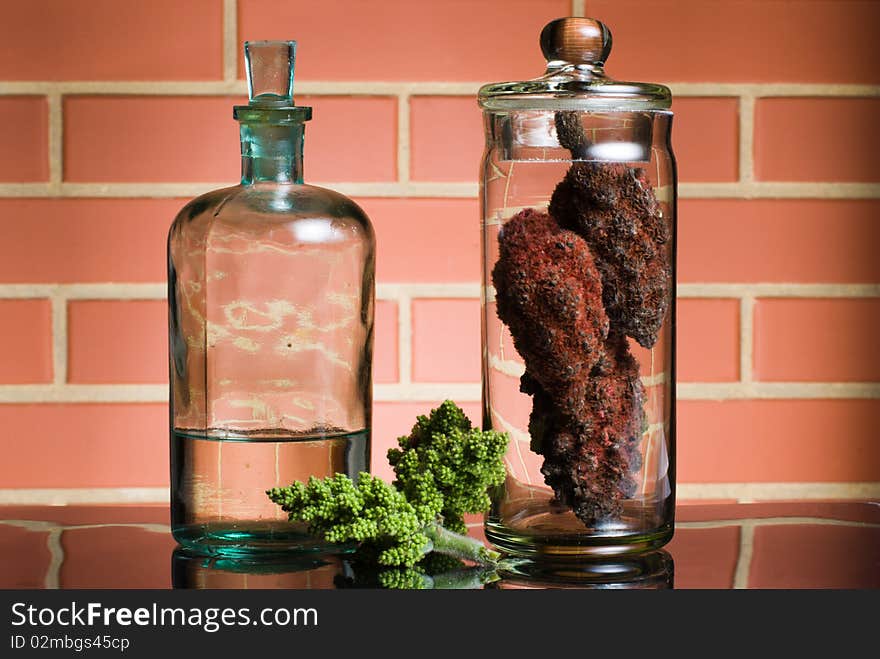 Old bottle with liquid and glass container on brick wall background. Old bottle with liquid and glass container on brick wall background