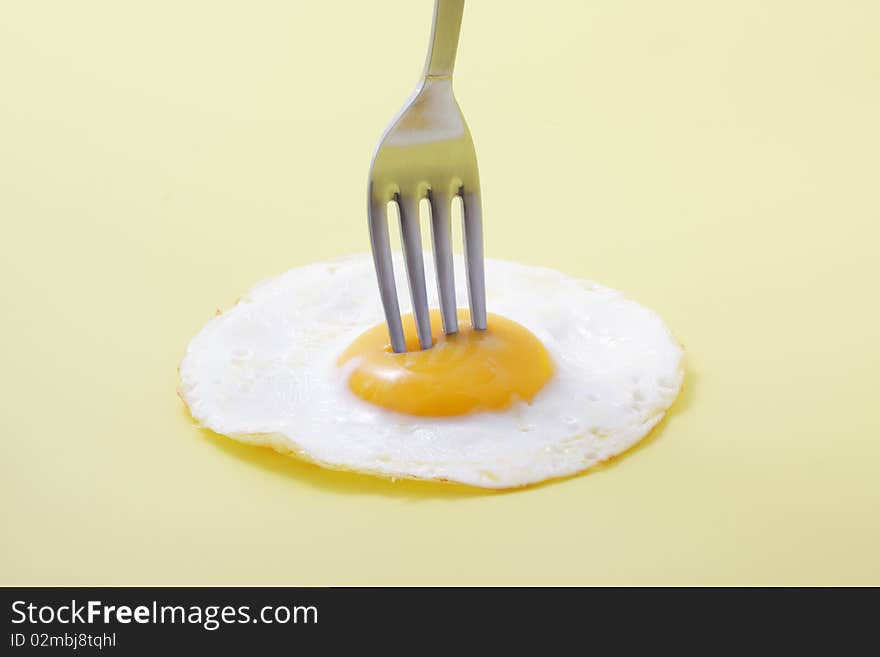 Isolated egg on yellow with fork