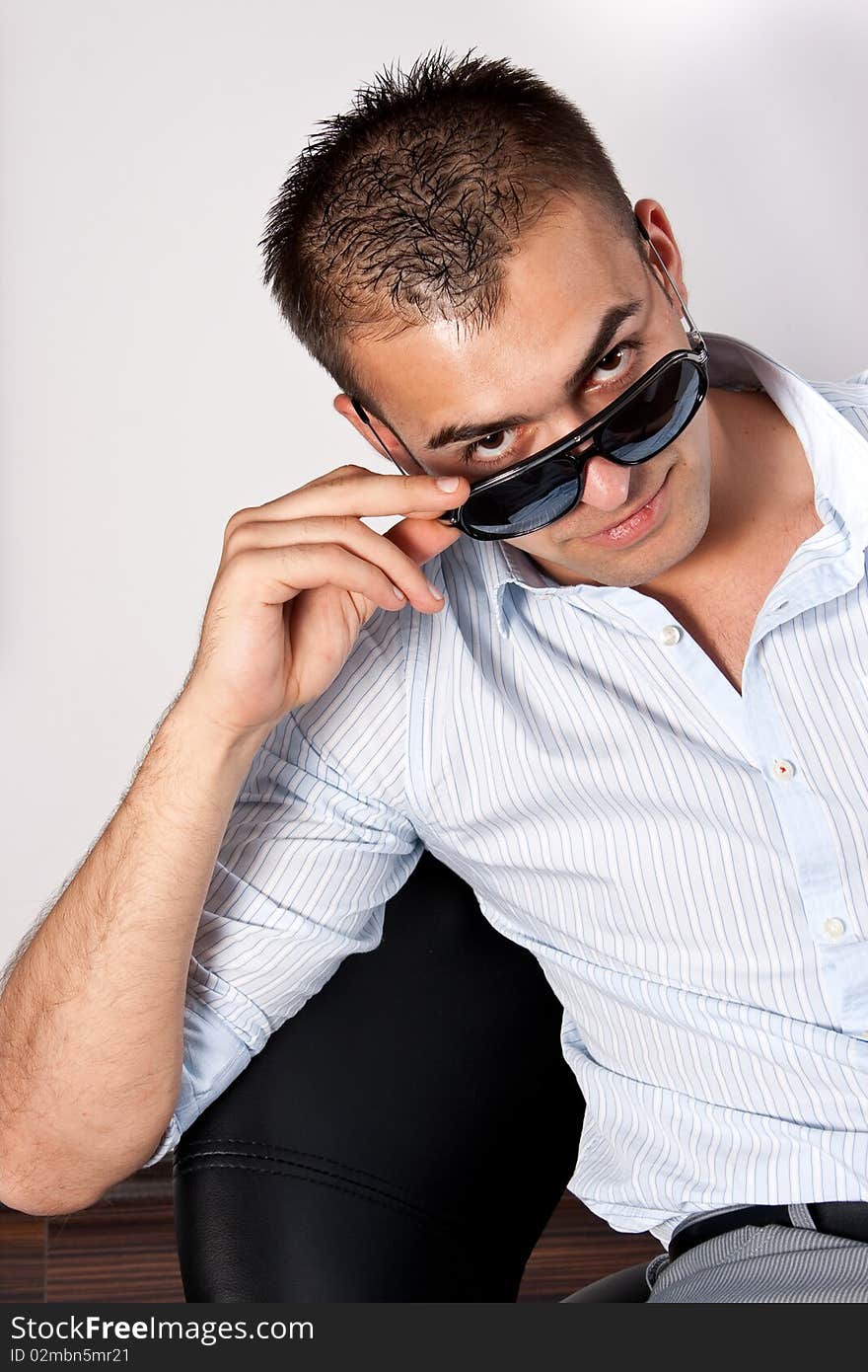 Young man with sunglasses sitting on an armchair