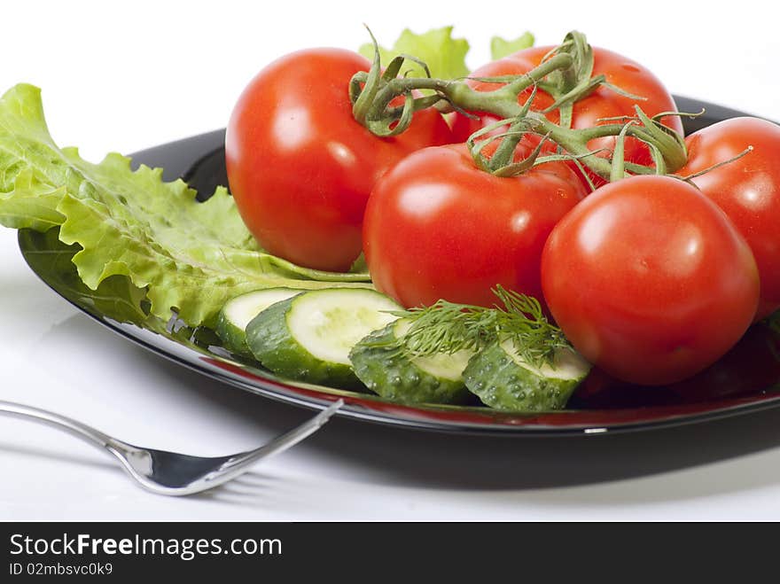 Studio shot of Fresh Vegetables with tomatos salad and cucumber in black plenty isolated on white