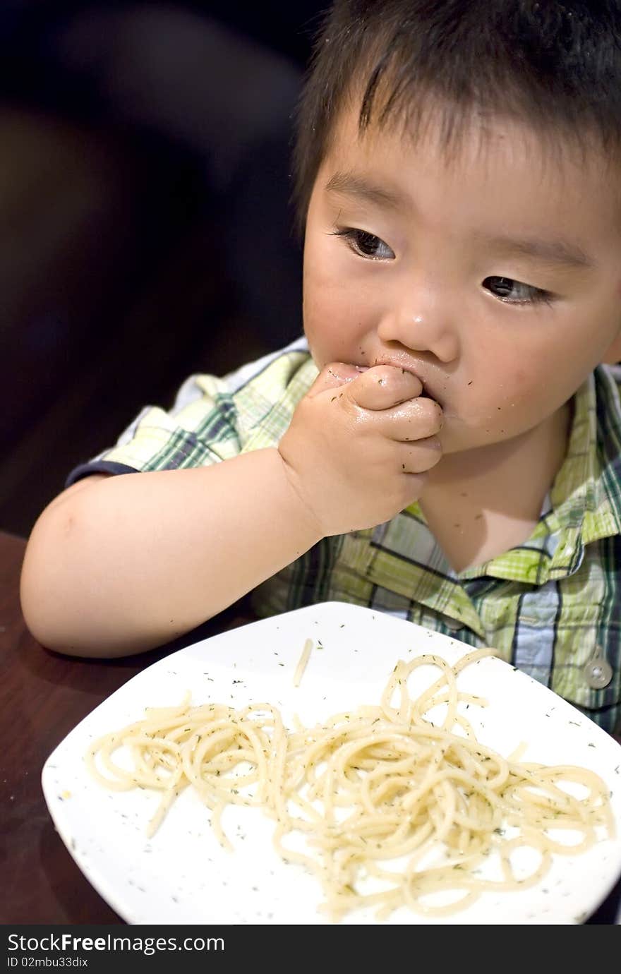 A eating baby to grab pasta