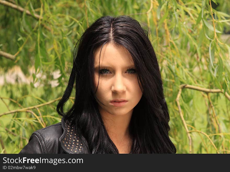 Attractive dark-haired young woman posing in front of a Willow tree. Attractive dark-haired young woman posing in front of a Willow tree