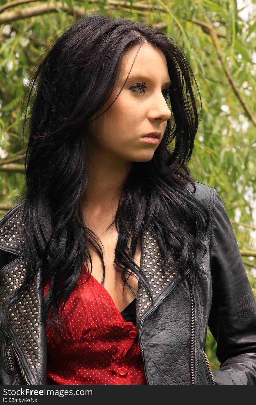 Attractive dark-haired young woman posing in front of a Willow tree. Attractive dark-haired young woman posing in front of a Willow tree