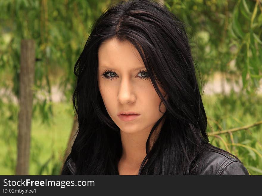 Attractive dark-haired young woman posing in front of a Willow tree. Attractive dark-haired young woman posing in front of a Willow tree