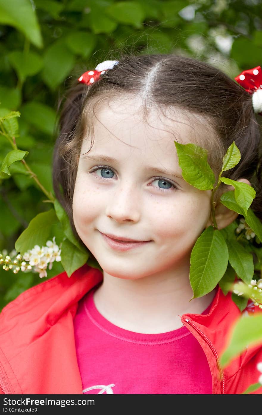 Portrait of a little girl with green leaves and blossom in background. Portrait of a little girl with green leaves and blossom in background.