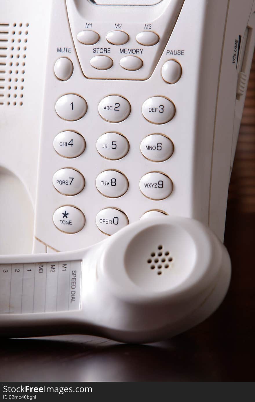 A closeup of a white telephone with the earpiece off the hook. A closeup of a white telephone with the earpiece off the hook