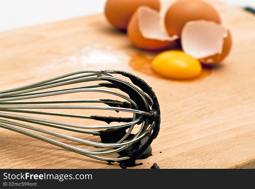 Spatula used in mixing a bowl of chocolate cake mix along with the fresh eggs are featured. Spatula used in mixing a bowl of chocolate cake mix along with the fresh eggs are featured.