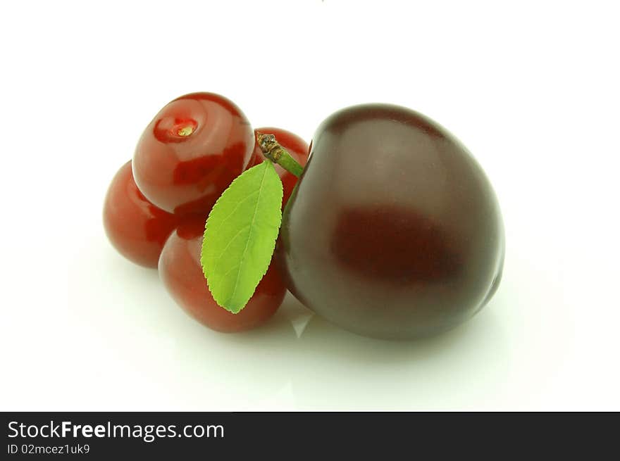 Ripe cherries and plum with leaf  background. Ripe cherries and plum with leaf  background