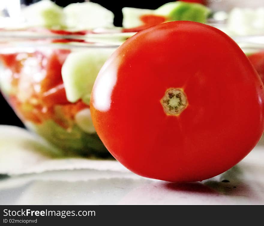 Tomato infront of homemade greek salad. Tomato infront of homemade greek salad