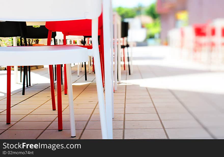 Photo of red, white and black plastic chairs in bar on open air