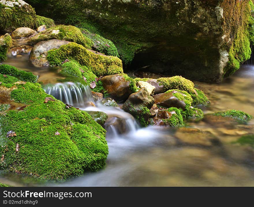 Long exposure shot of the blurred water and green rocks. Long exposure shot of the blurred water and green rocks