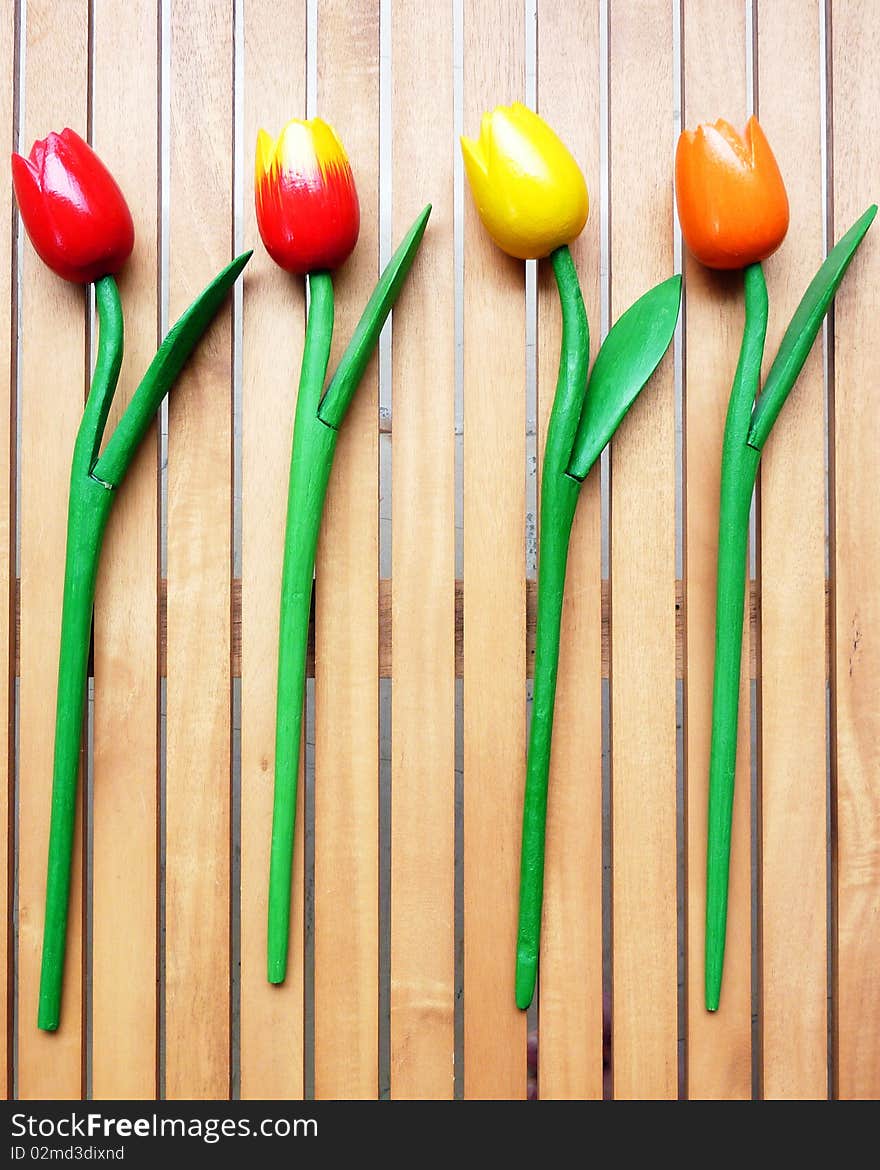 Colorful fake tulips on wooden background