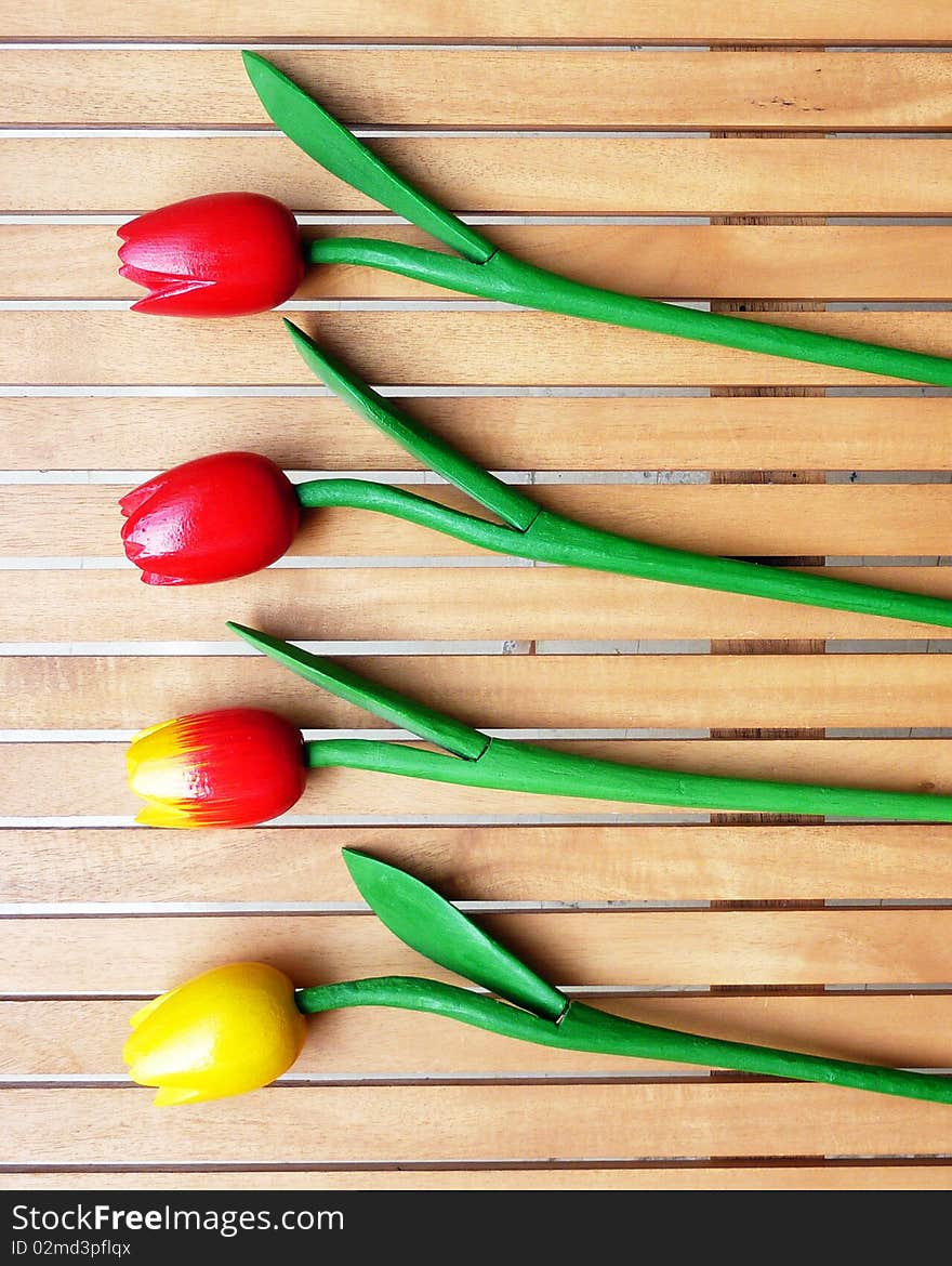 Four fake tulips on wood background