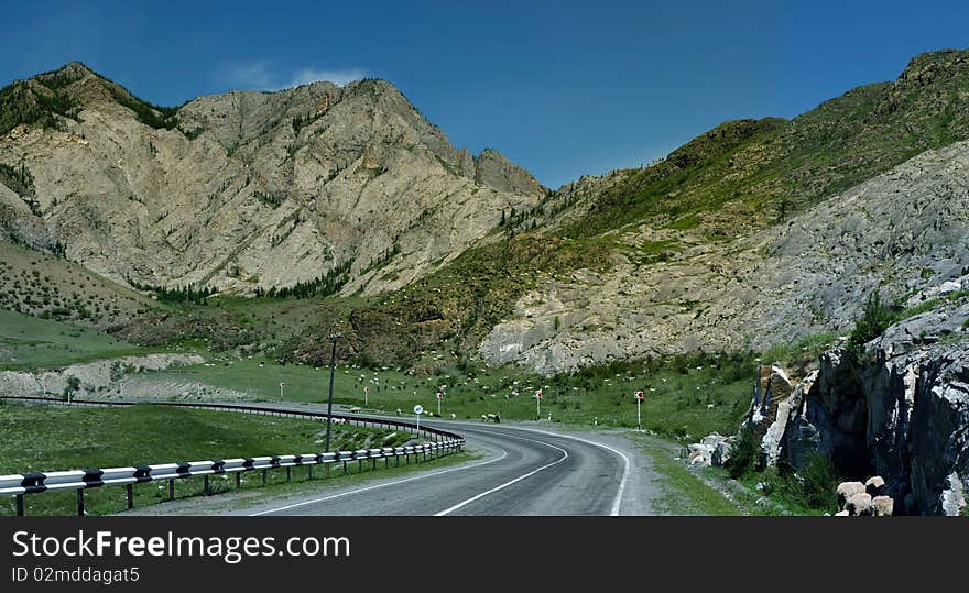 The road is laid at bottom of mountains. The road is laid at bottom of mountains