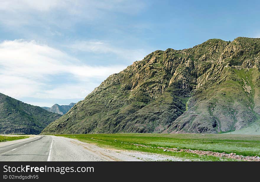 The road is laid at bottom of mountains. The road is laid at bottom of mountains