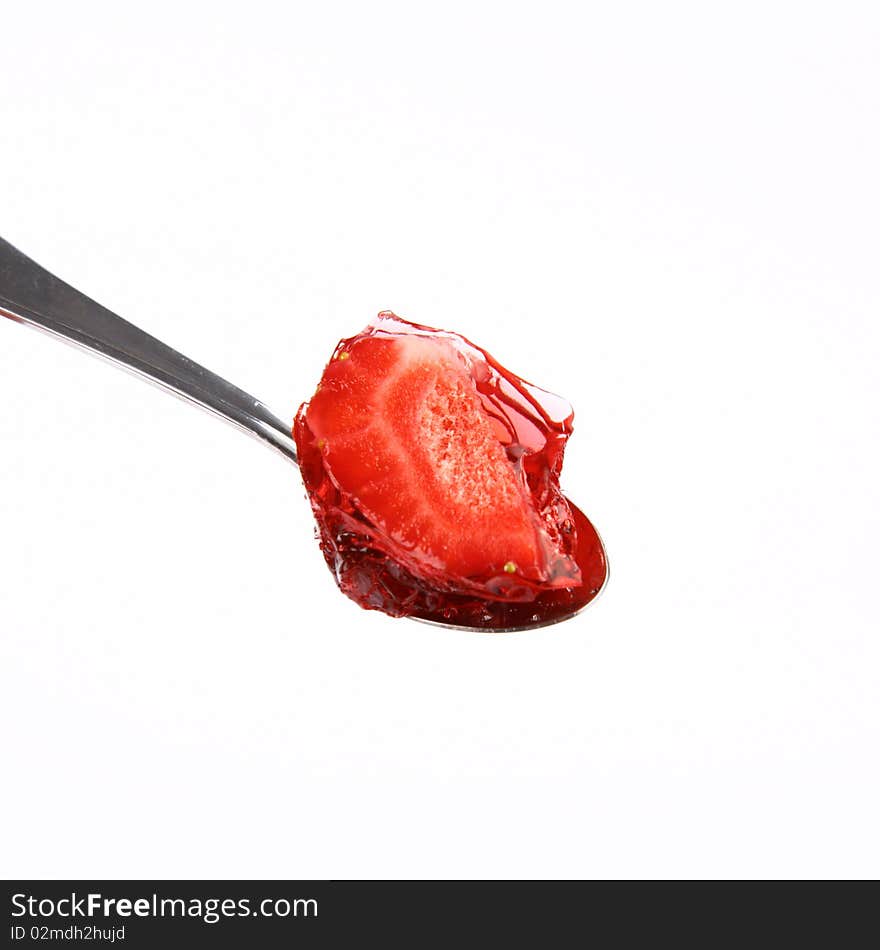 Strawberries covered with jelly on a spoon