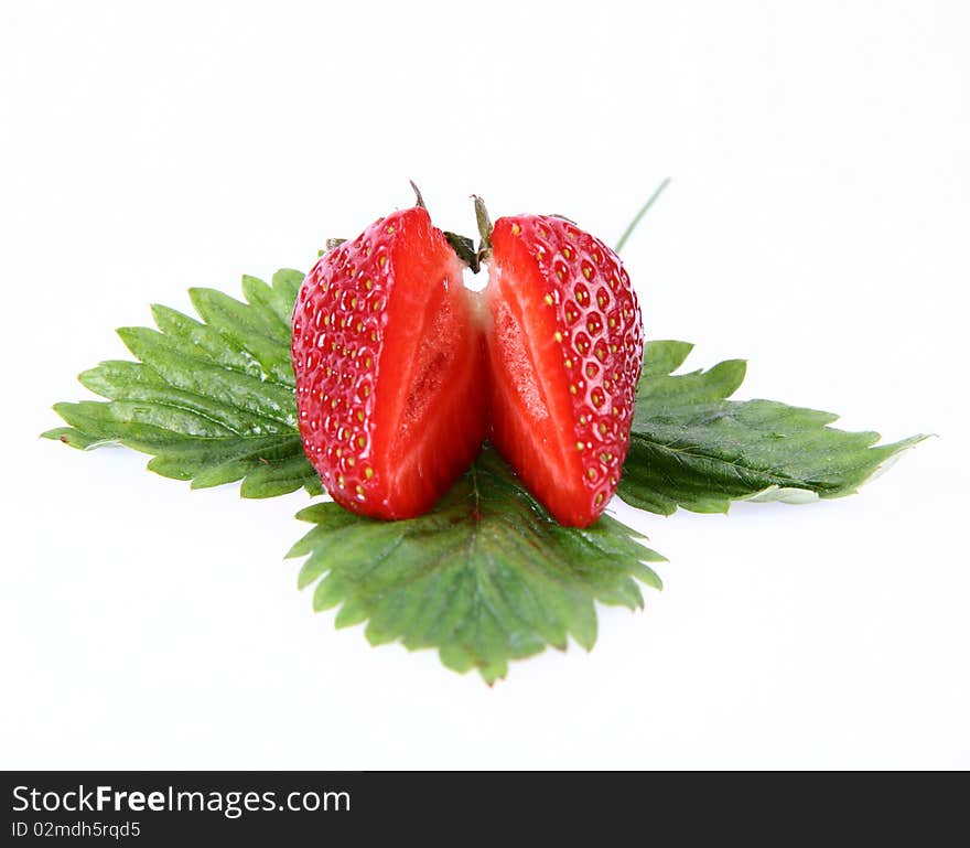 Strawberry on a leaf cut in half on white background