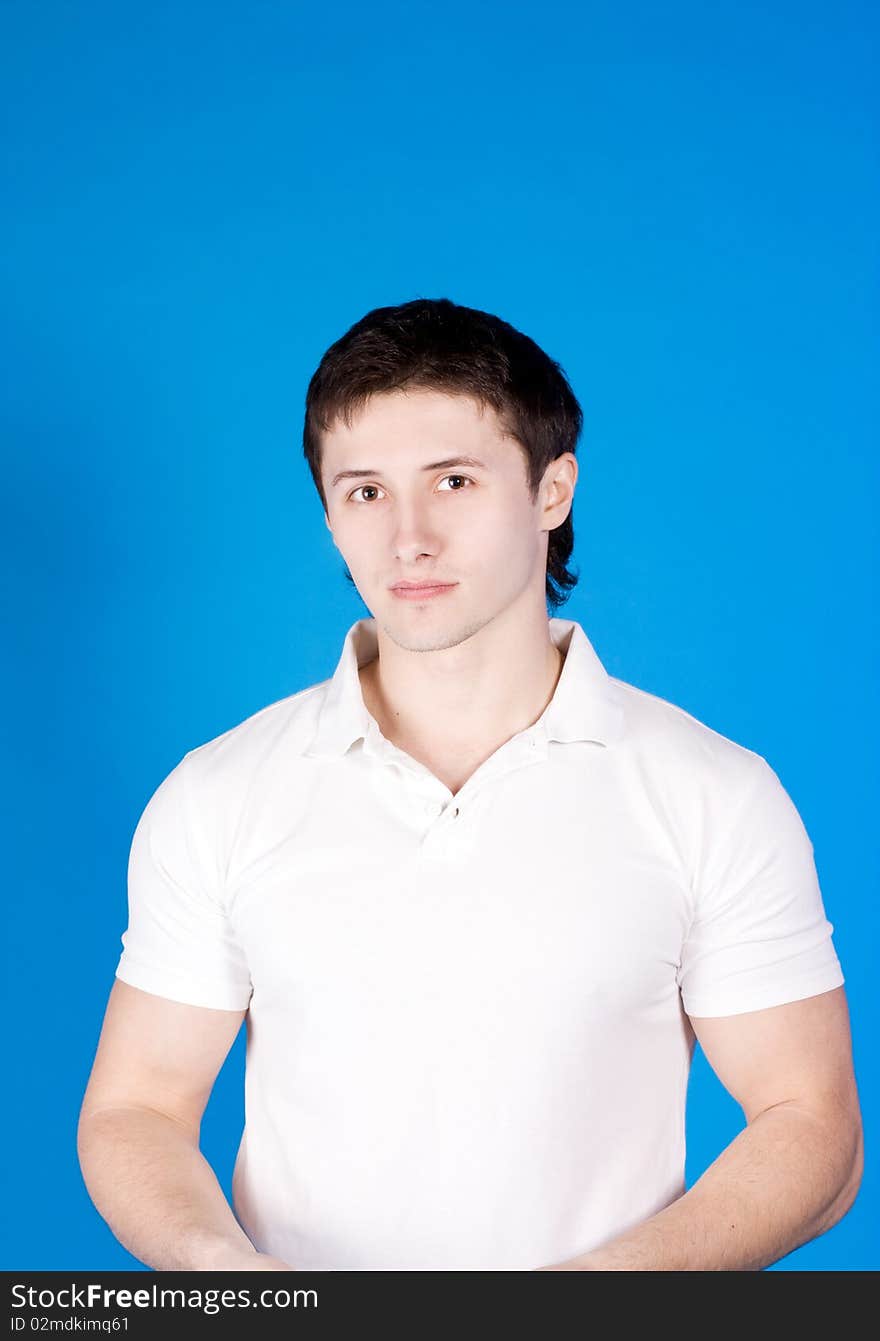 A brave young man on a blue background with a white shirt in the studio. A brave young man on a blue background with a white shirt in the studio