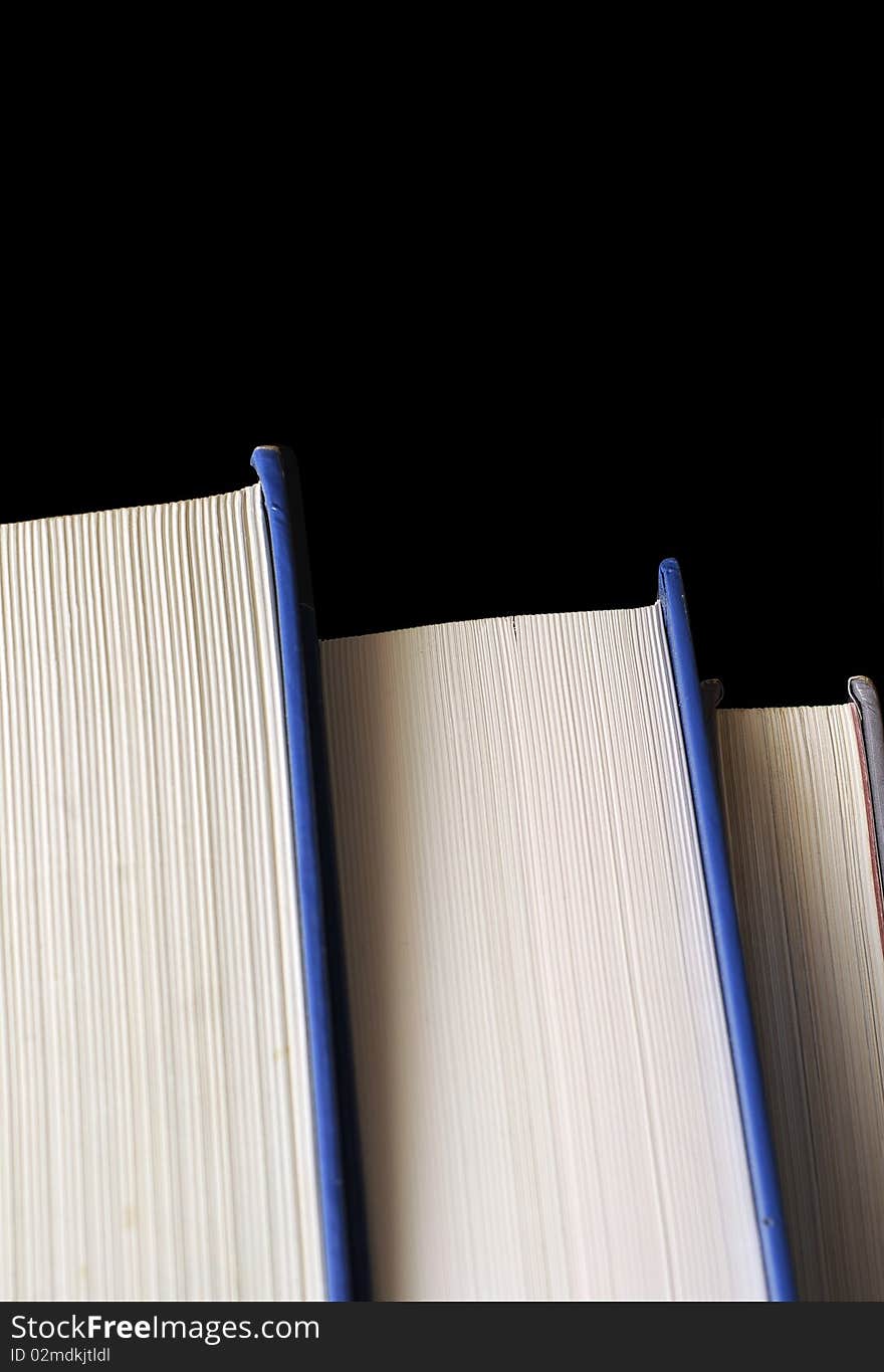 A stack of thick hardcover textbooks isolated on pitch black background. A stack of thick hardcover textbooks isolated on pitch black background