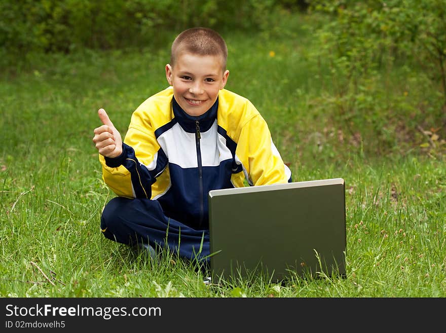 The boy with the computer on a grass