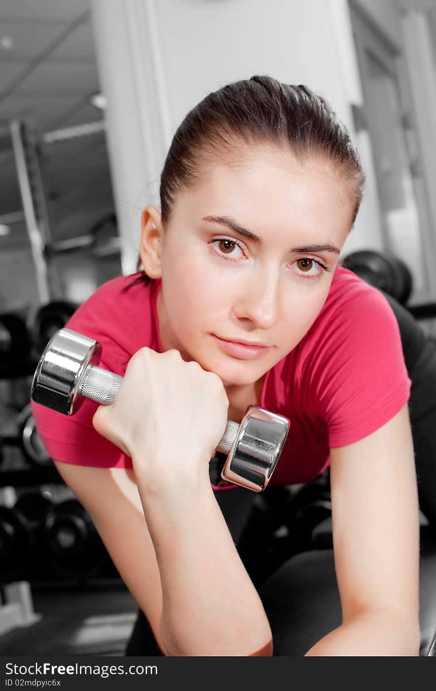 Pretty young woman training with dumbbells in a gym